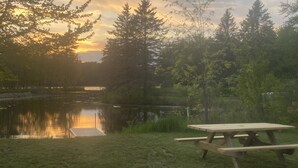 Een picknicktafel aan een rustig meer, met bomen op de achtergrond.
