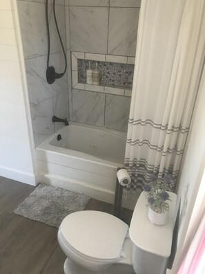 Een bad/douchecombinatie, handdoeken, zeep, shampoo