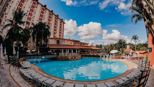 A swimming pool with lounge chairs, a restaurant, and a tall hotel building. - Hotsprings Hotel BVTUR (Caldas Novas)