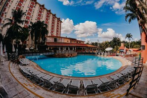 A swimming pool with lounge chairs, a restaurant, and a tall hotel building. - Hotsprings Hotel BVTUR (Caldas Novas)