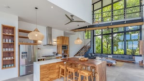 Una cocina amplia con una isla central, armarios de madera y un ventanal grande con vistas a la vegetación.