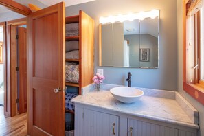 A bathroom with a vanity, a large mirror, and a towel rack.