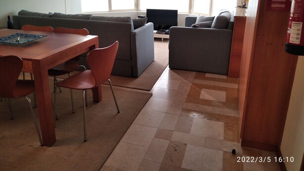 A living room with a sofa, a TV, and a dining table with chairs.