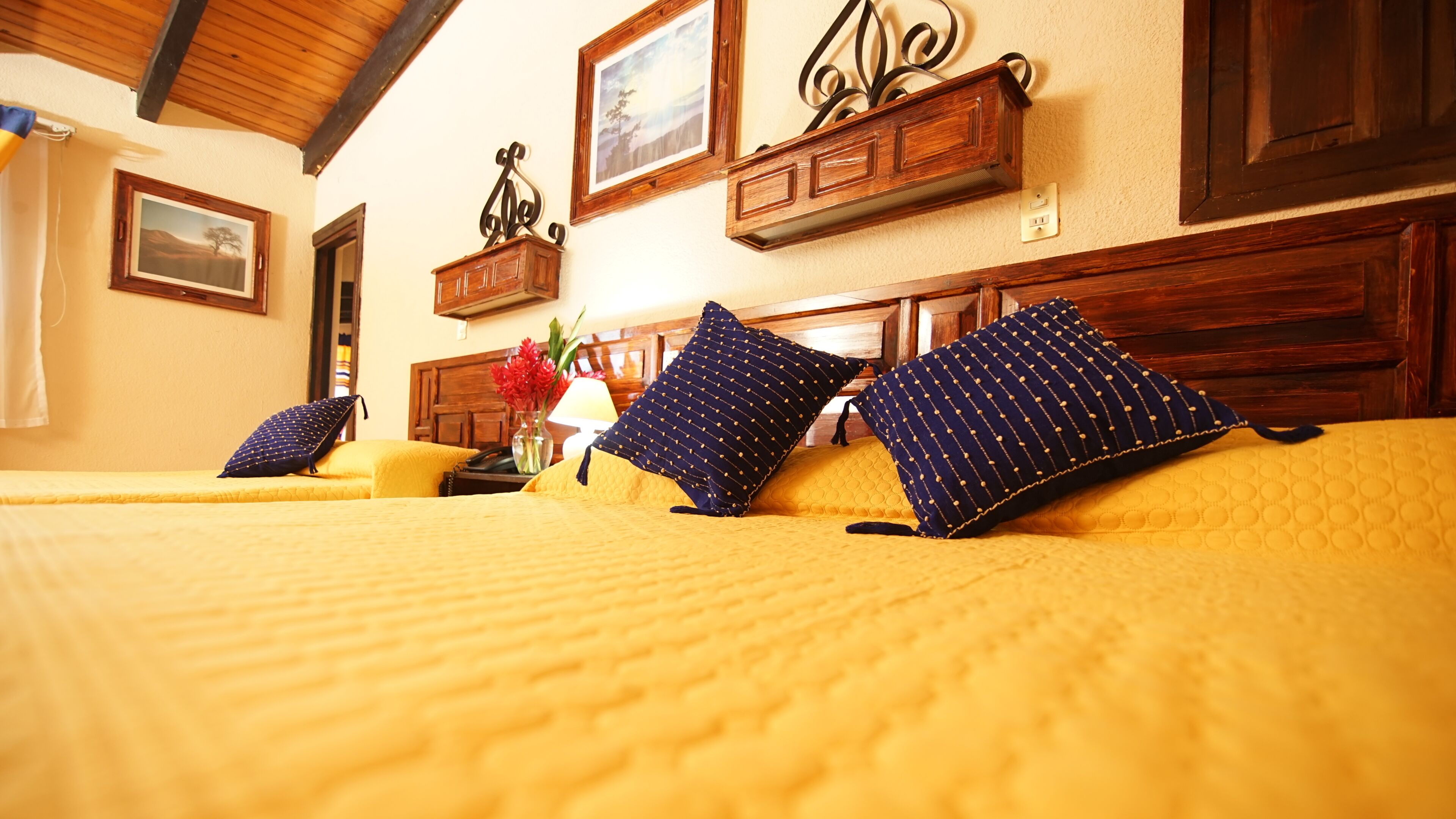 A hotel room with two beds, wooden headboards, and a wooden ceiling.