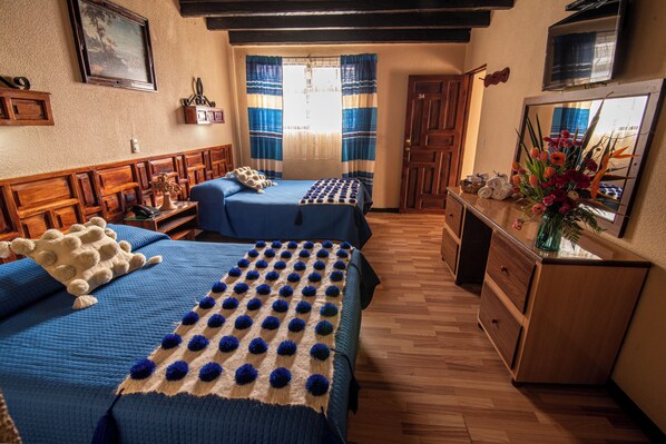 Ein Zimmer mit zwei Betten, Holzmöbeln, einem Schminktisch und einem Spiegel.