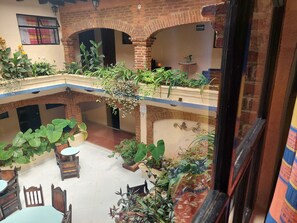 Ein mehrgeschossiges Atrium mit Ziegelbögen, Topfpflanzen und Holzmöbeln.