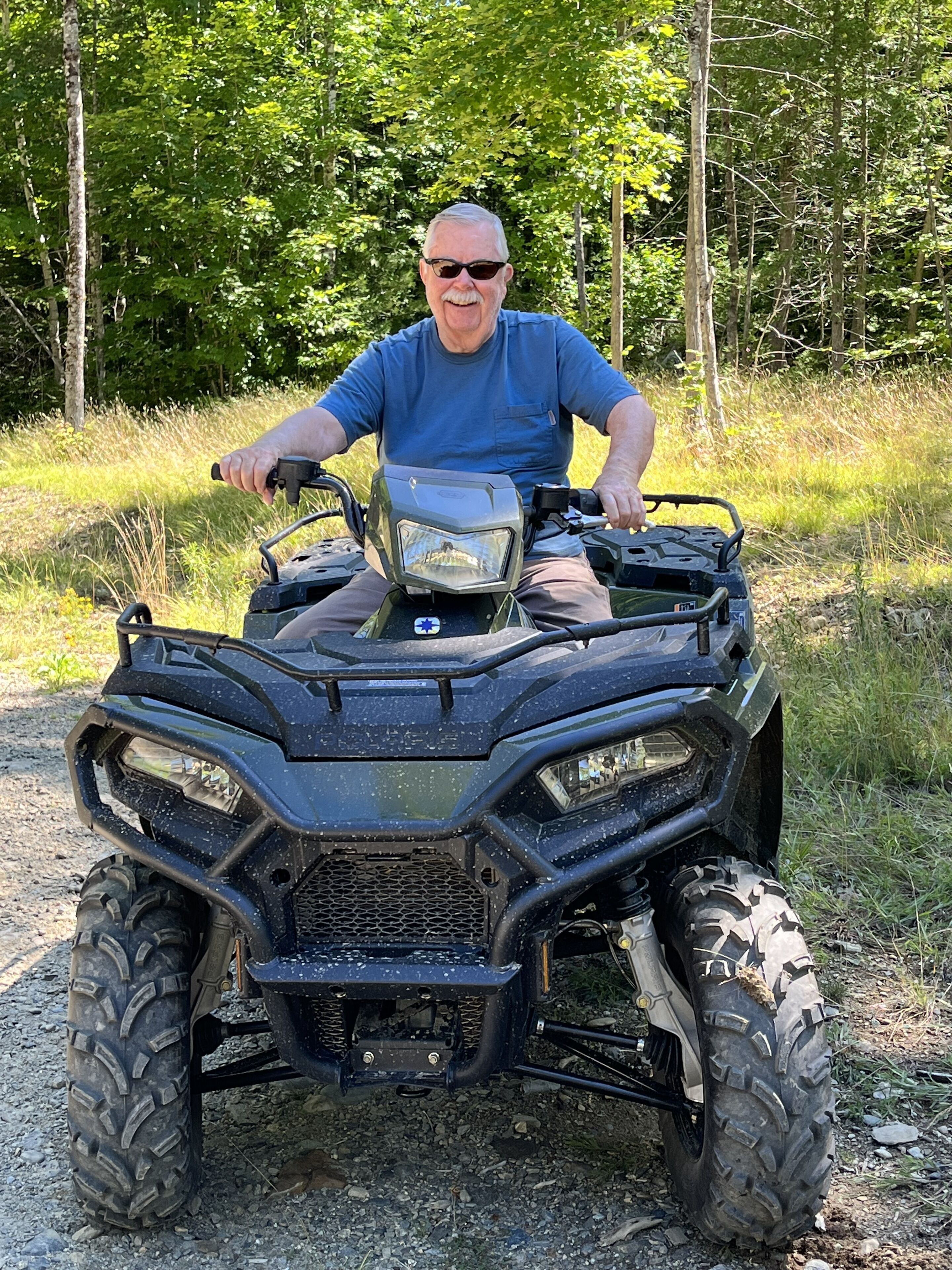 A person sitting on an ATV in a forested area.