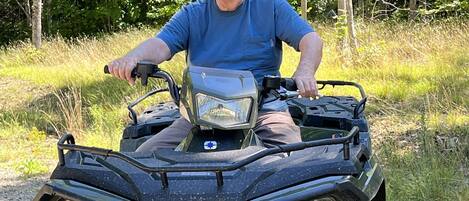 A person sitting on an ATV in a forested area.