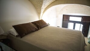 Une chambre à coucher avec un lit, une fenêtre et un mur en pierre.