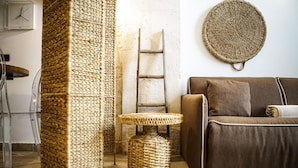 Un salon avec un canapé marron, un tapis en fibres naturelles, une petite table ronde et une horloge murale.