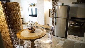Une cuisine avec une table ronde en bois, des chaises transparentes, un réfrigérateur et un four.