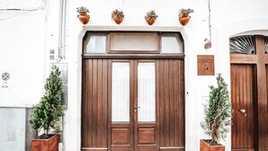 Un bâtiment doté d’une grande porte double en bois, d’une enseigne portant le numéro 5, et de deux plantes en pot de chaque côté de l’entrée.
