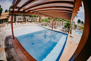 A swimming pool with lounge chairs and a covered area. - Diroma Internacional Resort - BVTUR (Caldas Novas)
