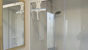 Een badkamer met een douchecabine van glas, een spiegel en een handdoekhouder.