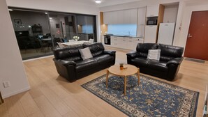 Ein modernes Wohnzimmer mit zwei schwarzen Ledersofas, einem kleinen runden Tisch und einem blauen Teppich mit Muster.