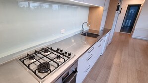 Eine moderne Küche mit einem Edelstahl-Gasherd, einer Spüle und weißen Schränken.