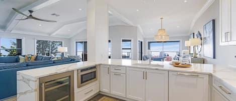 A modern kitchen with white cabinetry, a marble island, and a built-in oven.