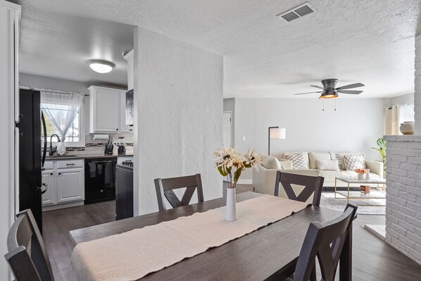 A modern kitchen with white cabinets and a dining area with a wooden table and chairs.