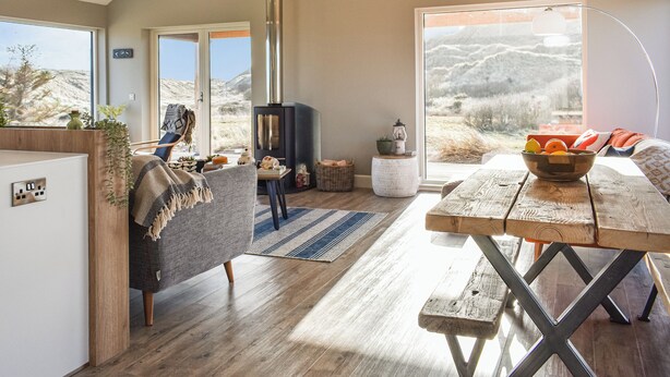 A spacious living area with a large window, a fireplace, and a dining table.