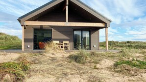 A modern house with a large glass door, wooden exterior, and a covered porch.