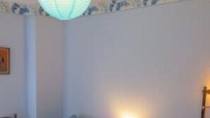 Un dormitorio con dos camas individuales, una mesita de noche con lámpara y un estante en la pared.