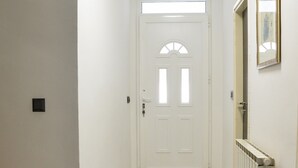 Ein Korridor mit einer weißen Tür, einem Heizkörper und einem gerahmten Bild an der Wand.