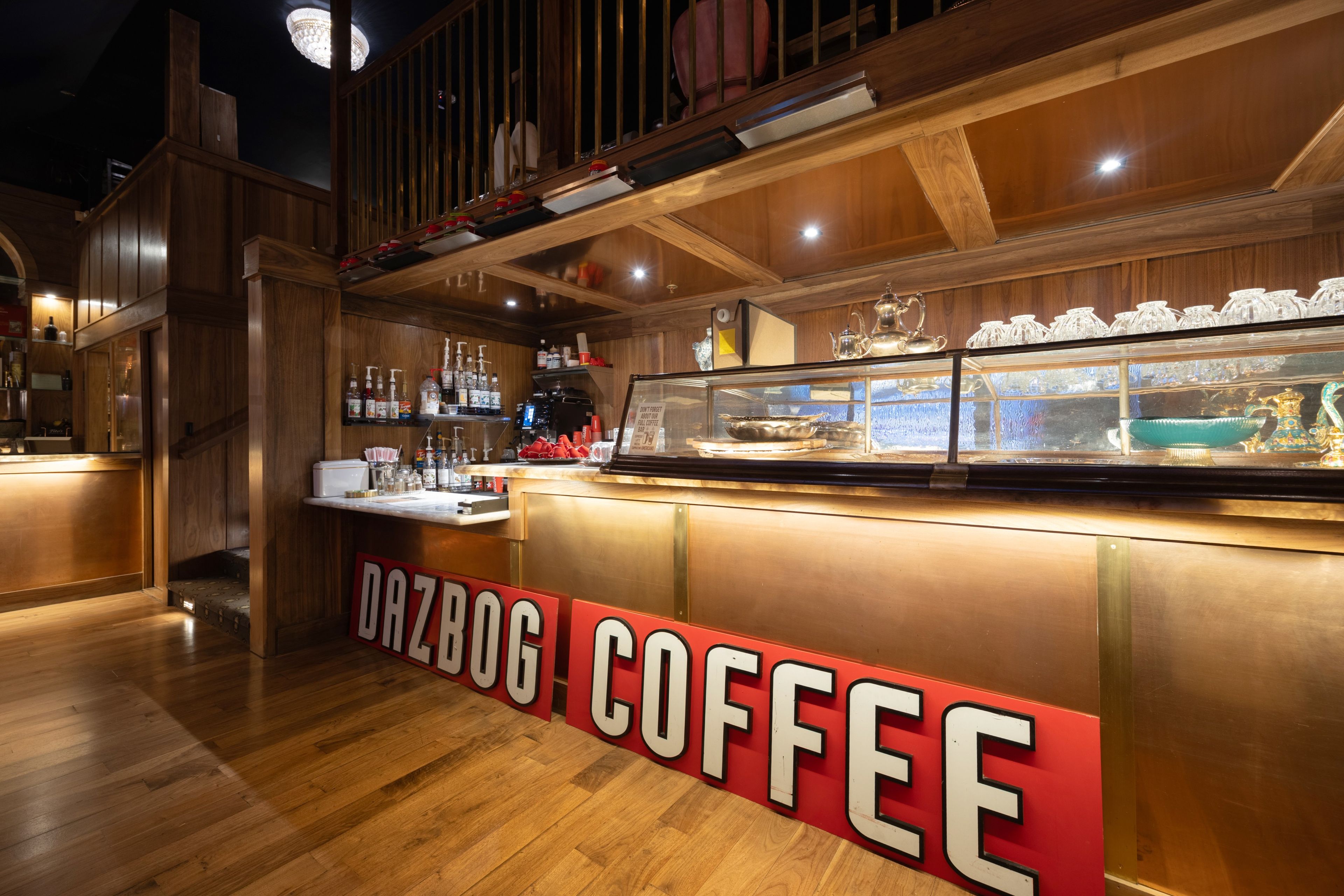 A bar area with a wooden interior, a glass display case with items, and a sign reading 'DAZDOG COFFEE'.