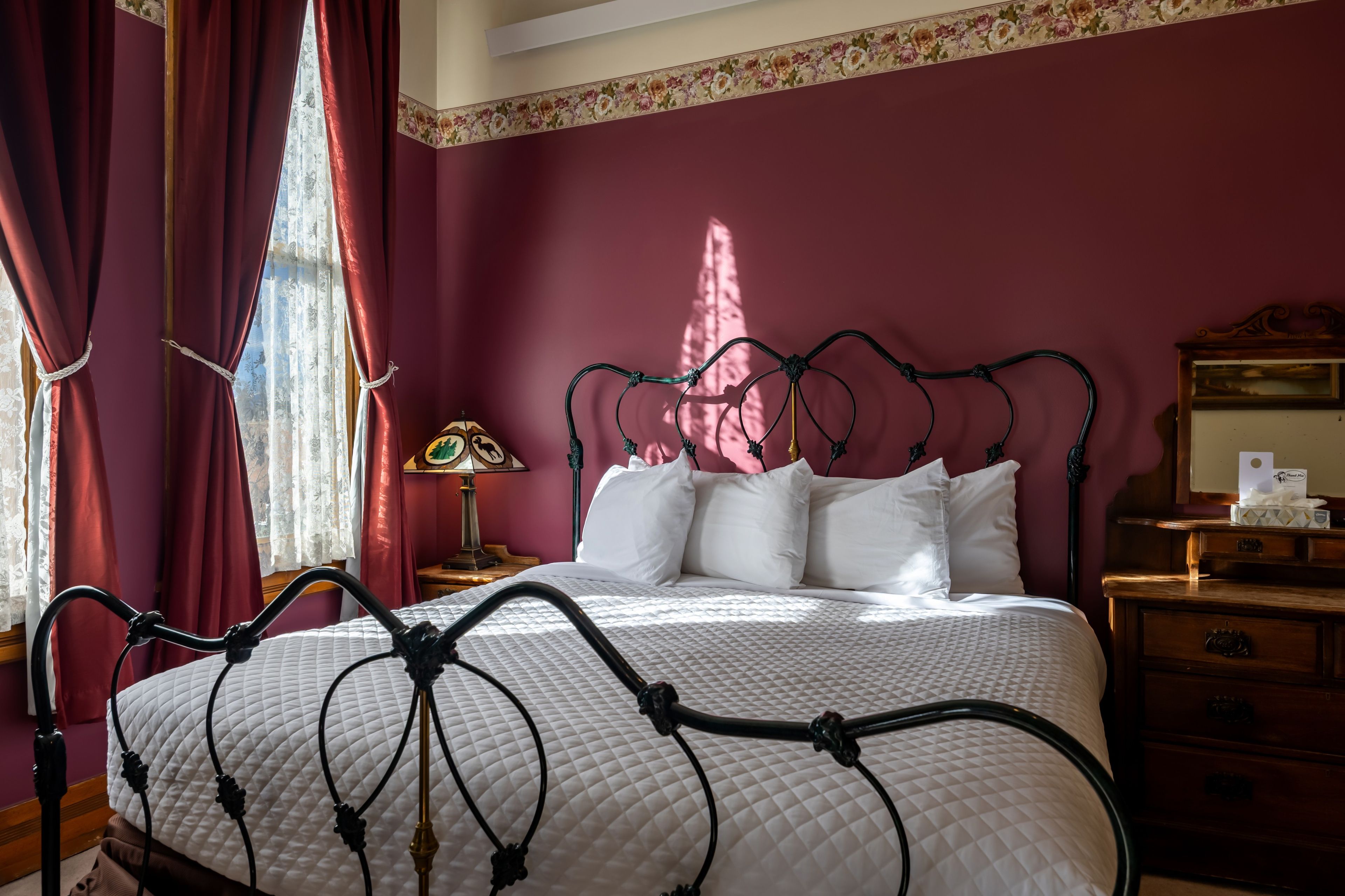 A bedroom with a bed, a nightstand, a lamp, and a dresser.