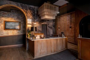 Una cocina moderna con salpicadero de mármol, armarios de madera e isla integrada con un lavamanos.