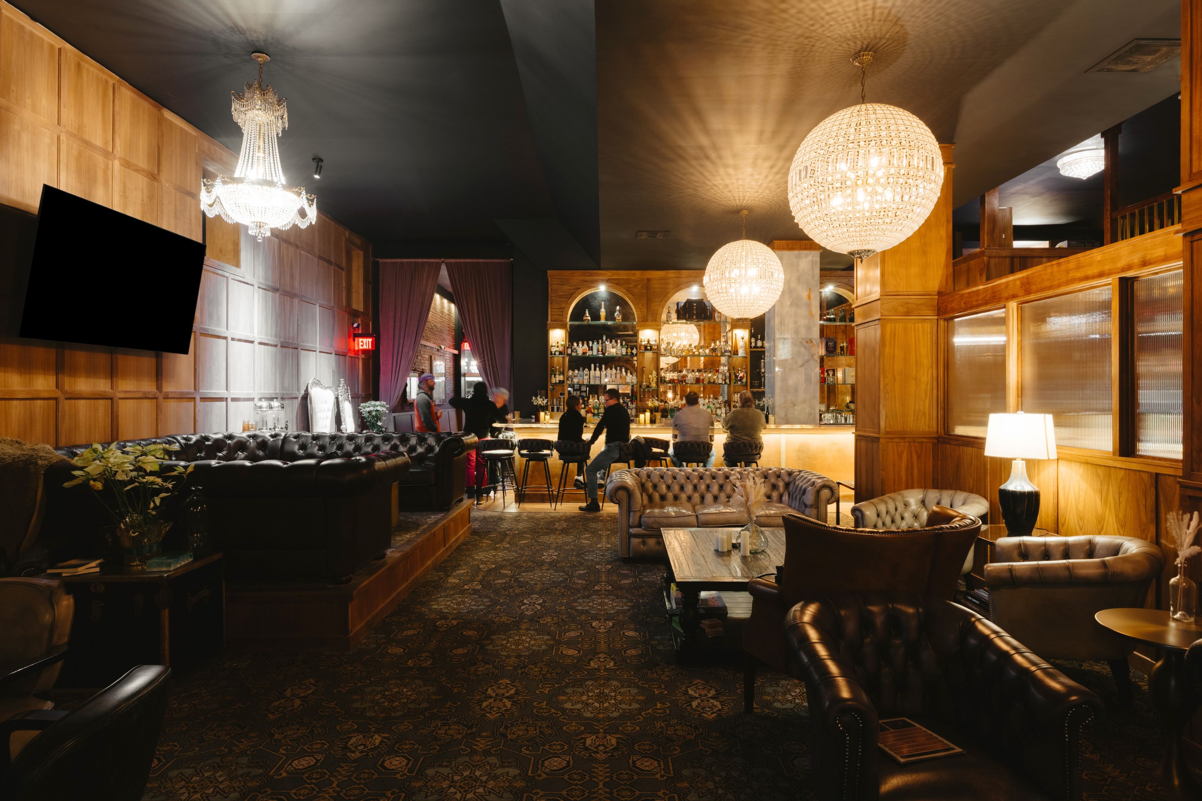 A bar area with leather seating, a bar counter, and a wine rack.