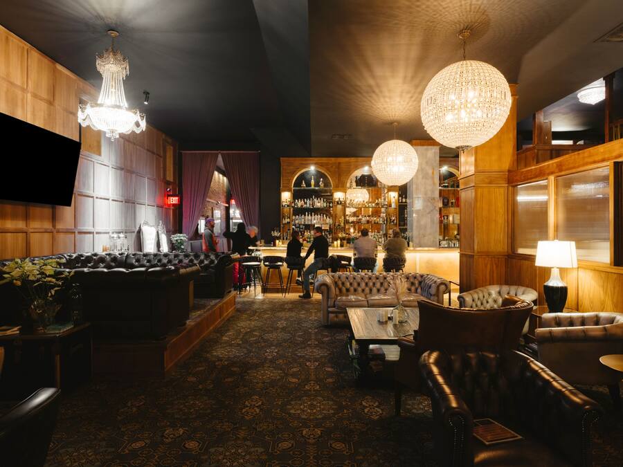 Zona bar con sedute in pelle, bancone e scaffalatura per vini.