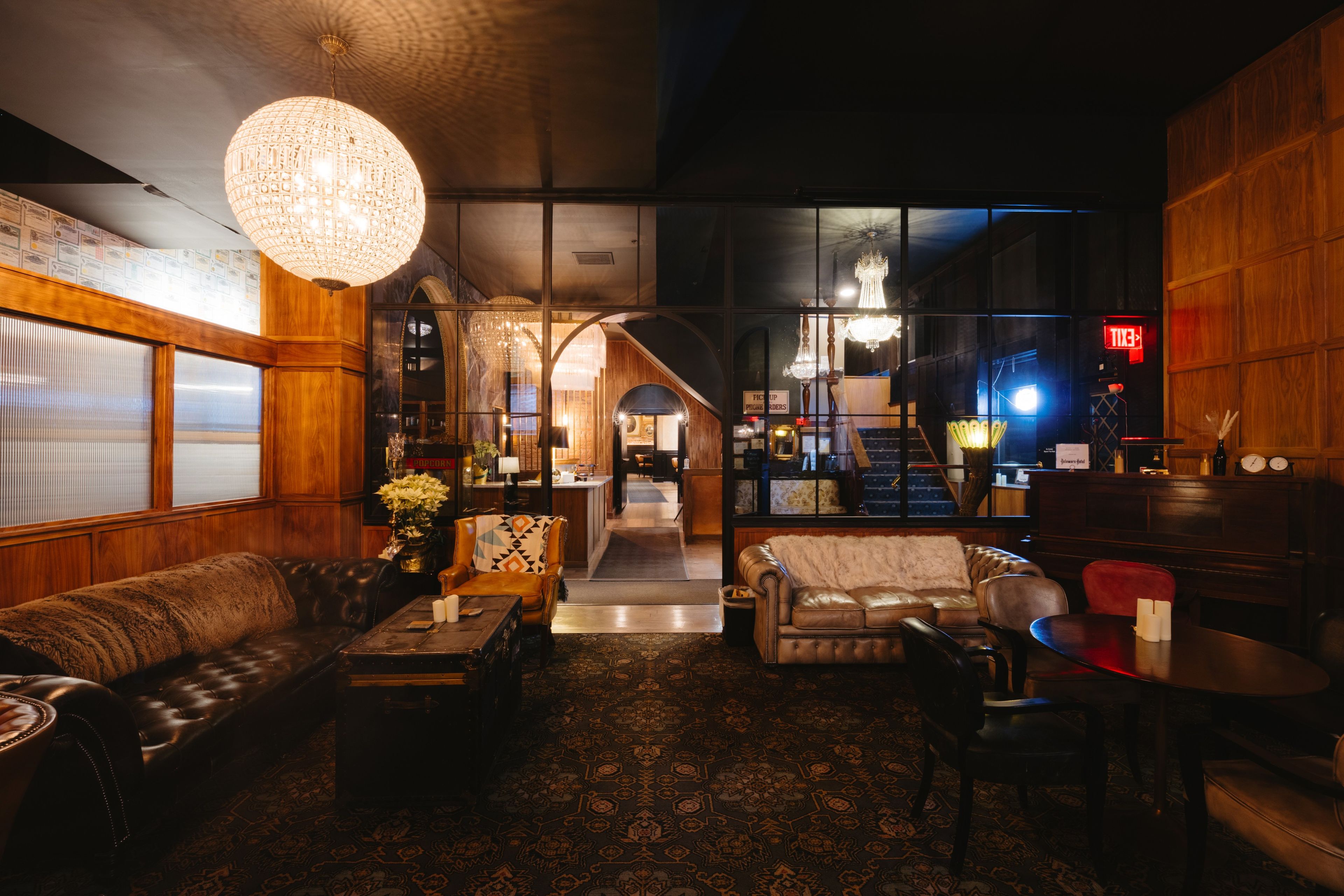 A hotel lobby with a leather sofa, a coffee table, and a chandelier. There is a staircase leading to the upper floor.
