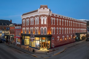 A historic red brick building with a corner entrance, a visible storefront, and a street-level seating area. - The Delaware Hotel (Leadville)