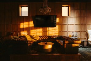 A cozy living room with a leather sofa, a coffee table, and a flat-screen TV mounted on the wall. - The Delaware Hotel (Leadville)