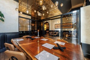 Un salón de conferencias con una mesa de madera, sillas de cuero y una araña.