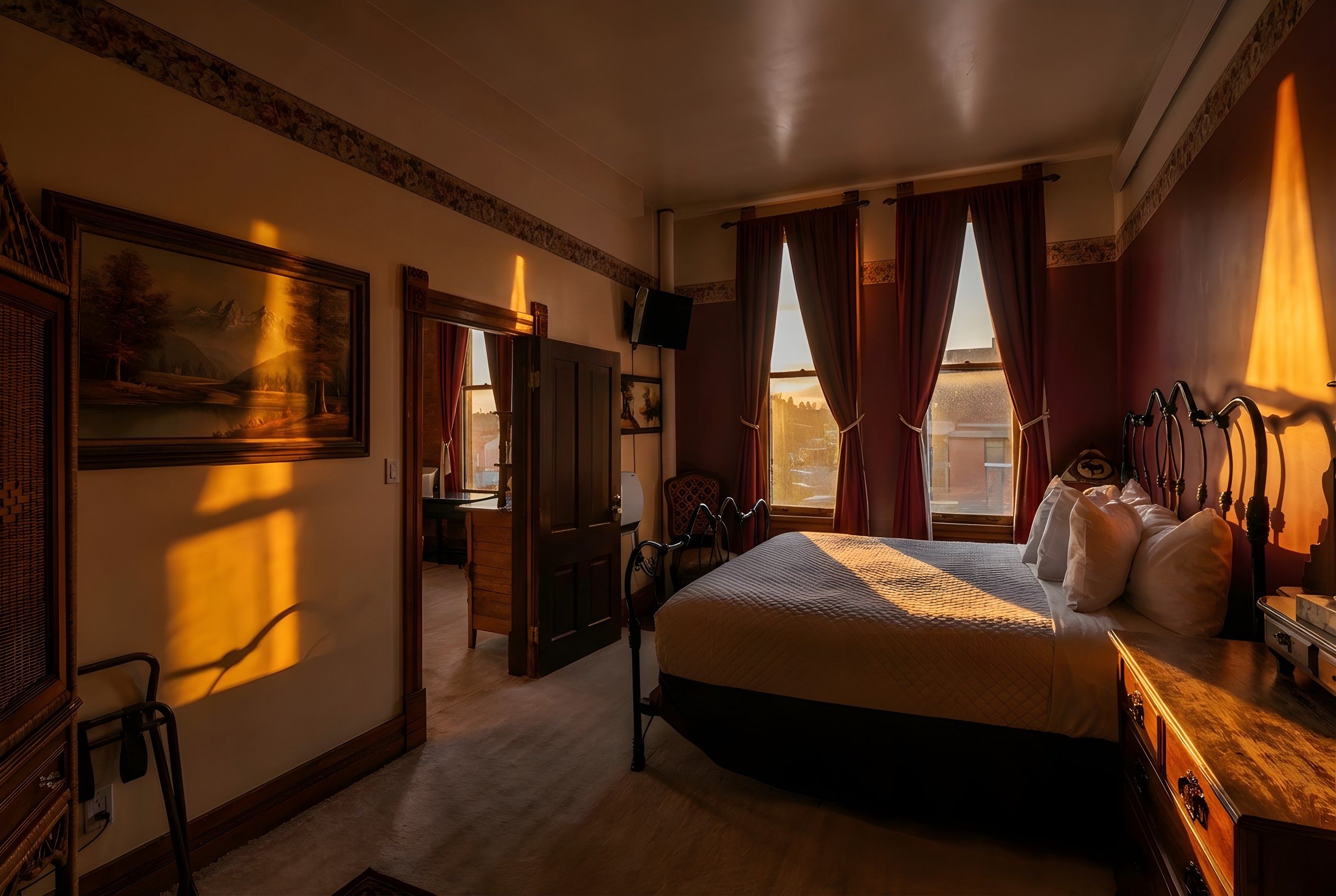 Hotellihuone, jossa on sänky, työpöytä, tuoli, televisio ja taulu seinällä.