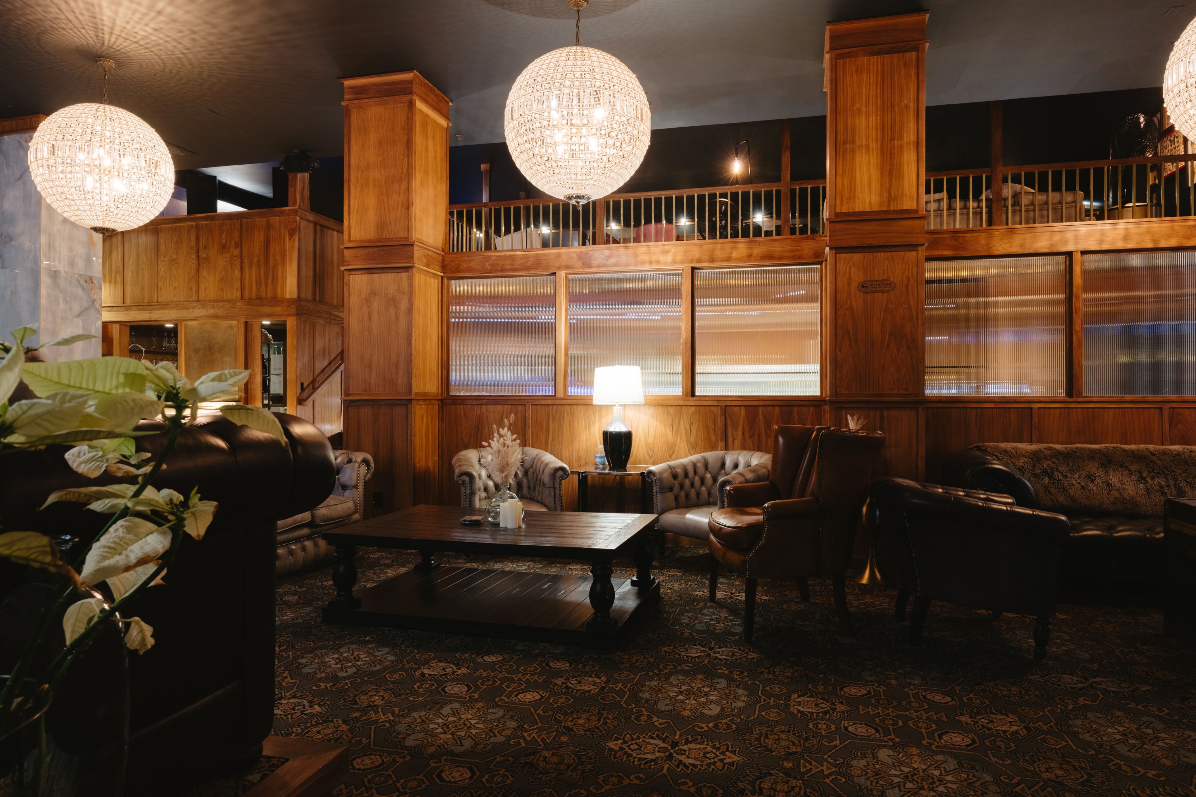 A room with a wooden staircase, leather furniture, and a patterned carpet.