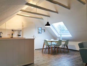 Une cuisine moderne dotée d’une verrière, de poutres en bois et d’un coin repas avec des chaises.