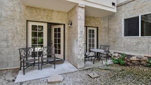 An outdoor patio with a stone wall, a bench, a table, and a door leading to a covered area. - Family Getaway ,Pool, Tubing, Skiing, & Ice Castles Villa 1002 (Midway)