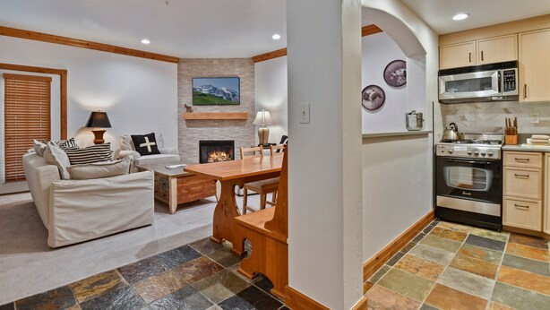 A living room with a fireplace, a dining table, and a sofa. - Family Getaway ,Pool, Tubing, Skiing, & Ice Castles Villa 1002 (Midway)