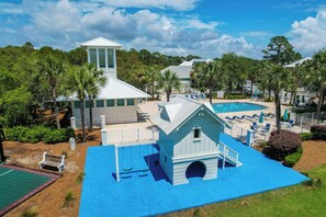 A resort with a swimming pool, a small building with a tower, and a playground area. - 213 Sandyshore - Carillon Lux Home, Guest Cottage, Beach Service, Steps to Beach (Panama City Beach)