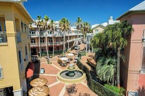 A courtyard with outdoor seating, palm trees, and a central fountain. - 213 Sandyshore - Carillon Lux Home, Guest Cottage, Beach Service, Steps to Beach (Panama City Beach)
