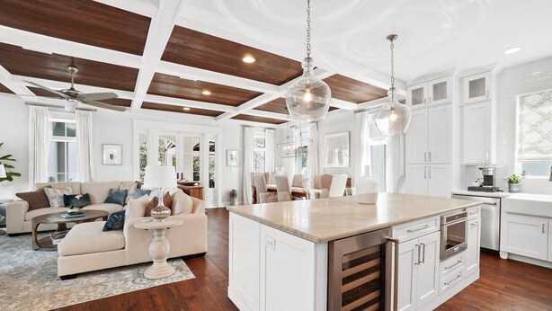 A spacious kitchen with white cabinetry, a large island, and a wooden ceiling.
