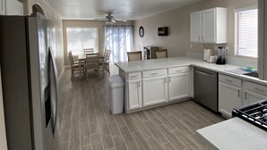 A modern kitchen with white cabinets, a built-in stove, and a dining area with a table and chairs. - One story, 3bedrooms. 15 min from Strip. Quiet & and safe. (Las Vegas)