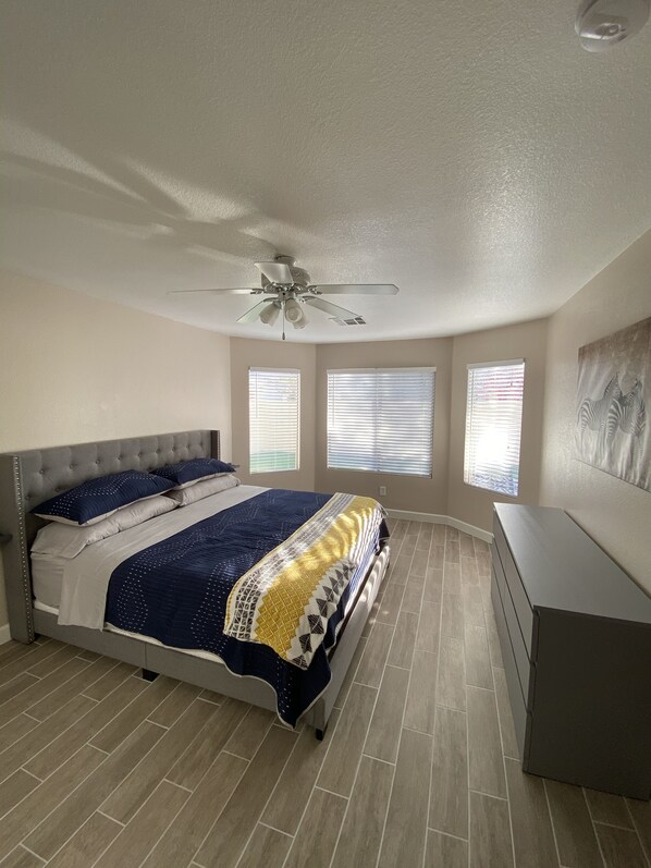 Une chambre à coucher avec un lit, un ventilateur de plafond et une commode.