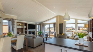 A spacious living area with a sofa, dining table, and chairs, a kitchen island, and large windows offering a view. - 2 bedroom accommodation in Addlethorpe, near Skegness (Addlethorpe, near Skegness)