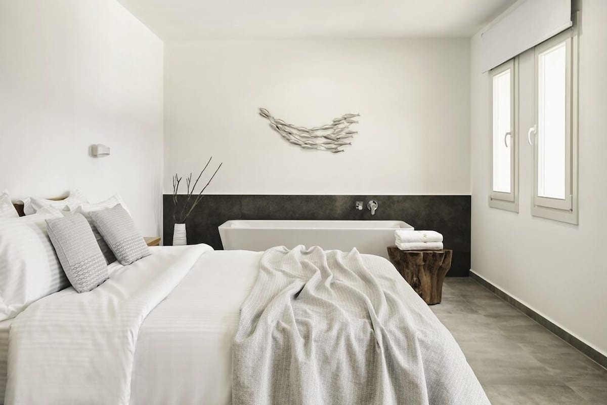 Ein modernes Schlafzimmer mit einem großen Bett, einer Badewanne und einem Fenster.