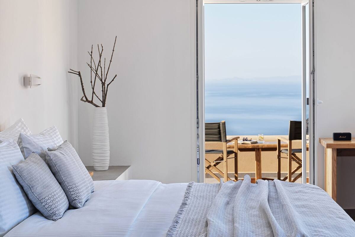 Ein Schlafzimmer mit einem Bett, einem Schreibtisch und Meerblick.