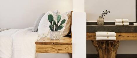 Une chambre moderne avec une table de chevet en bois, une plante succulente et un tabouret en bois.
