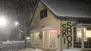 A snow-covered building with a neon sign reading "OPEN" and a sign that says "SHOP".